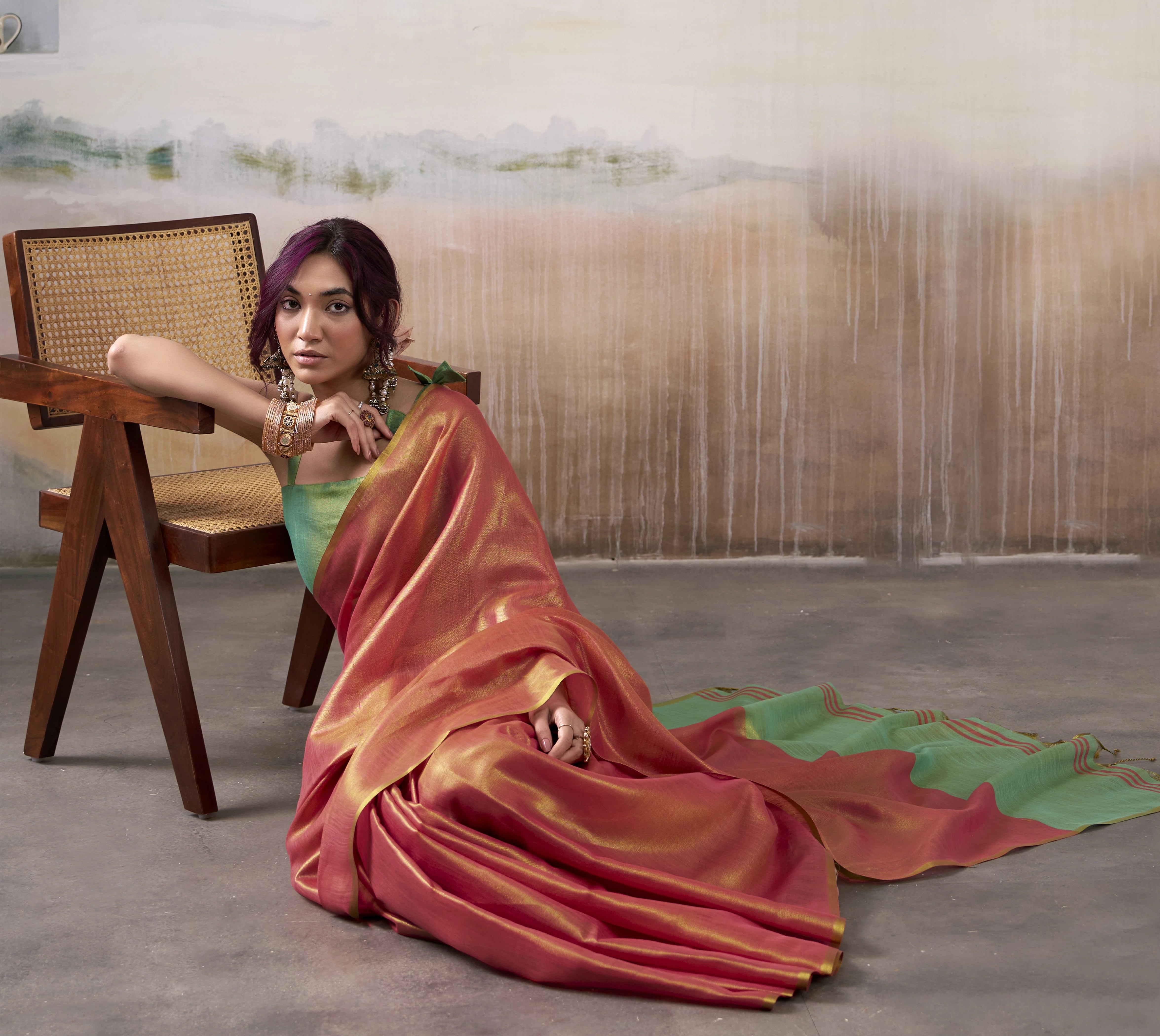 Woman in a red saree sitting on a chair with a blurred background